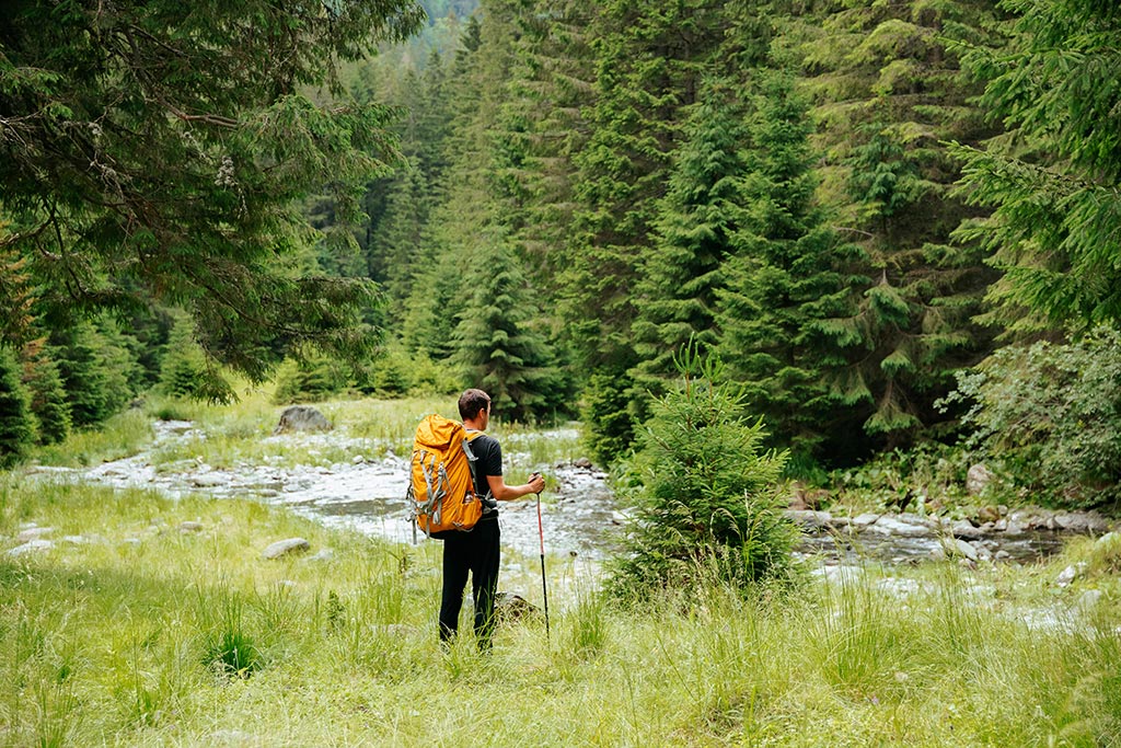 man hiking near stream